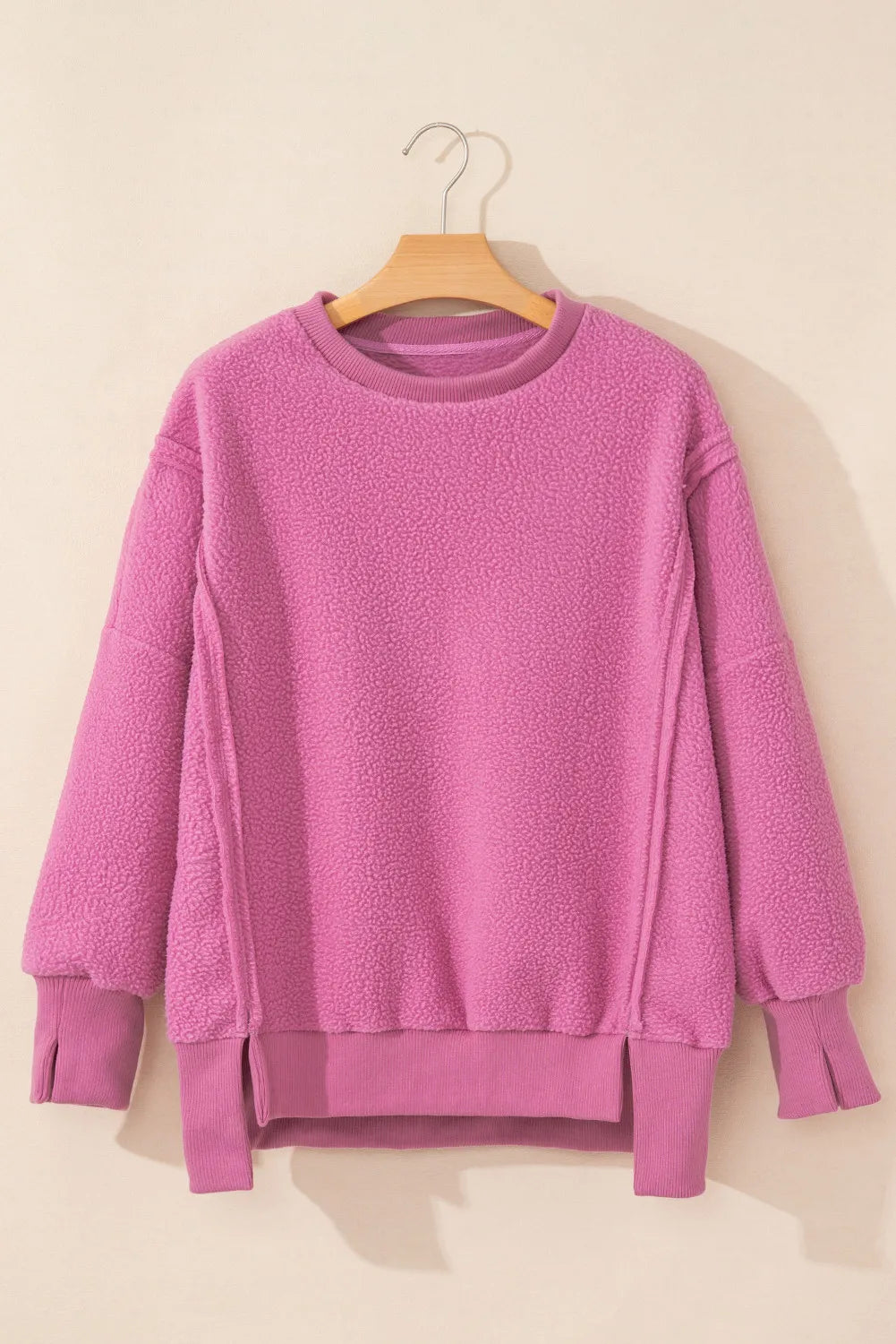 Pink slit round neck long sleeve sweatshirt with exposed seams and high-low hem.