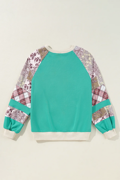 Printed round neck long sleeve blouse with teal and patterned sleeves.