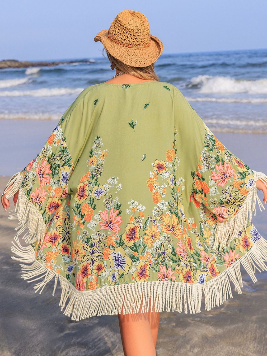 Plus size fringe open front cover-up with floral design, viscose material, beach background.