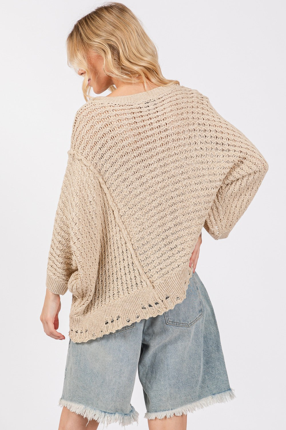 Distressed asymmetrical open stitch sweater with half sleeves and round neckline, worn by model.