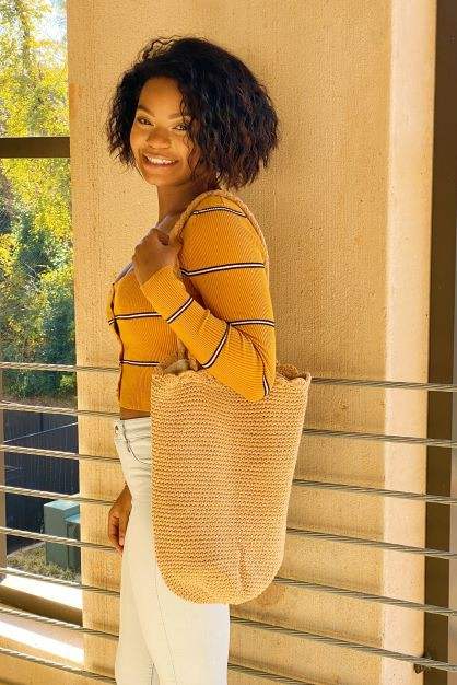 Knitted scalloped edge tote bag with braided strap and chic design.