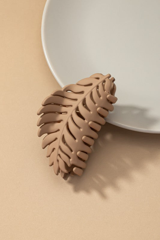 Feather-shaped matte acrylic hair clip on a plate.