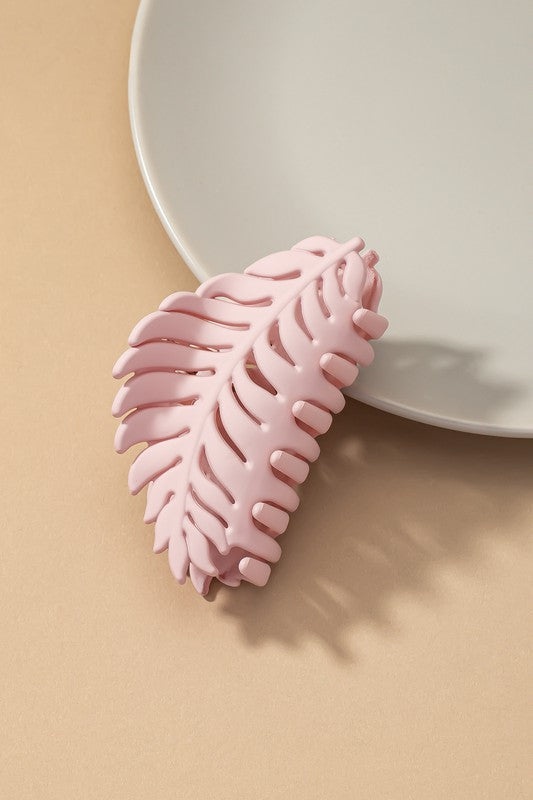 Feather Claw Hair Clip in matte pink acrylic resting on a plate.