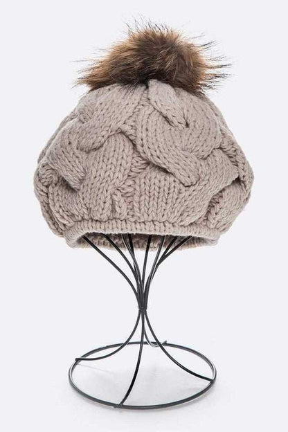 Large fur pom cable knit beret beanie with detachable faux fur pom and cotton composition.