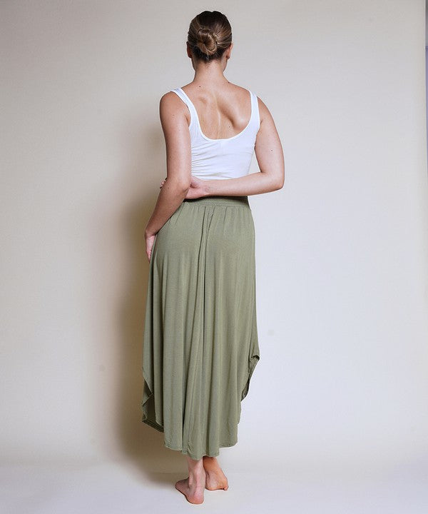 Green bamboo maxi skirt with smocked elastic waist worn by a woman facing away.