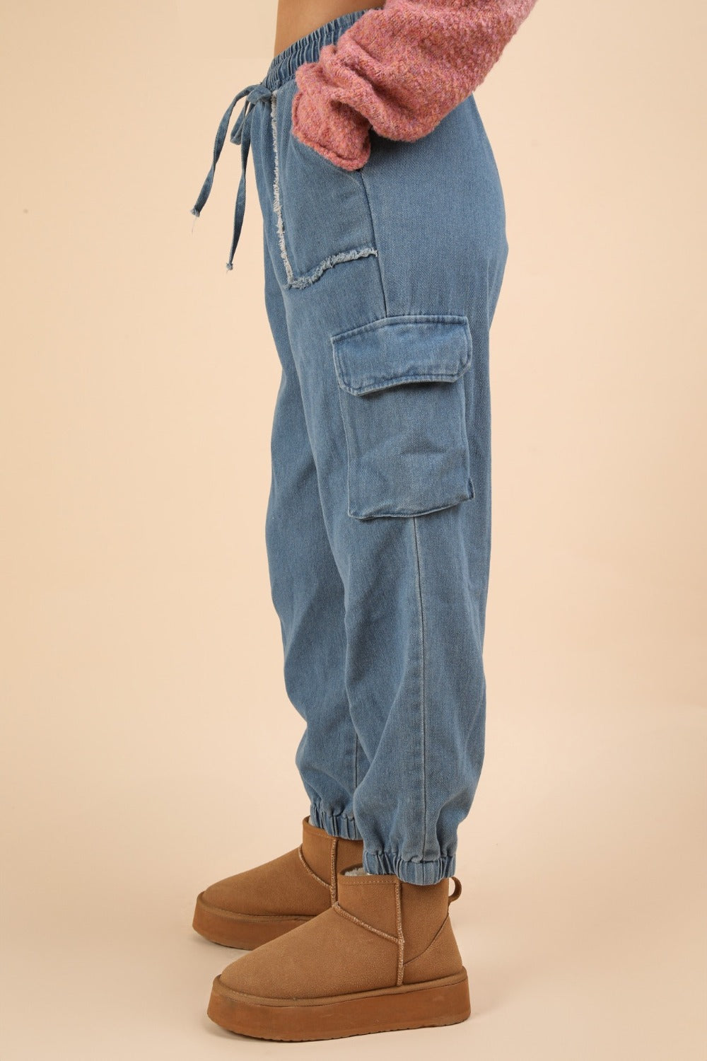 Washed drawstring jogger cargo jeans with side pockets and raw hem.