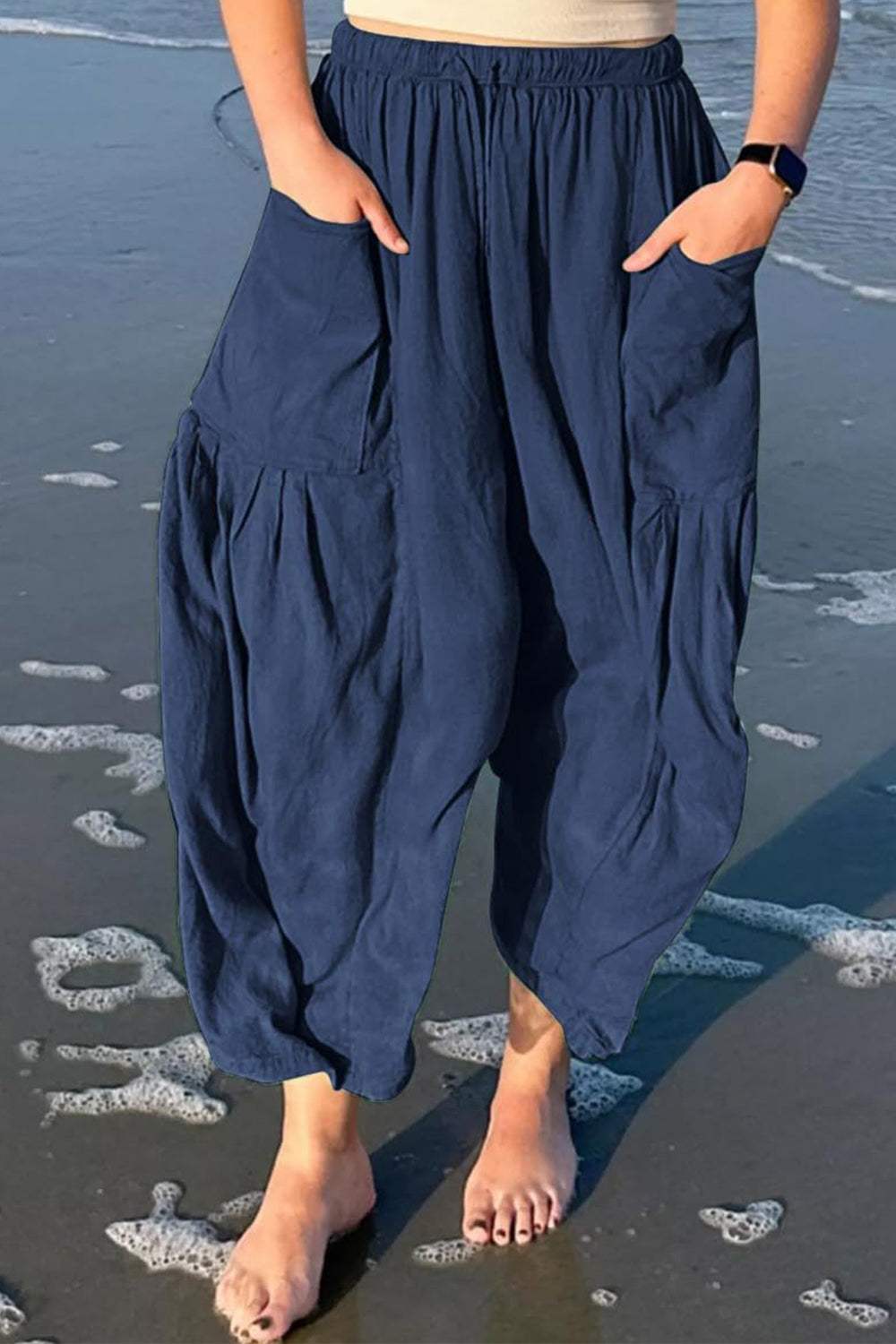 Boho wide leg harem pants with pockets, navy blue, beach setting.