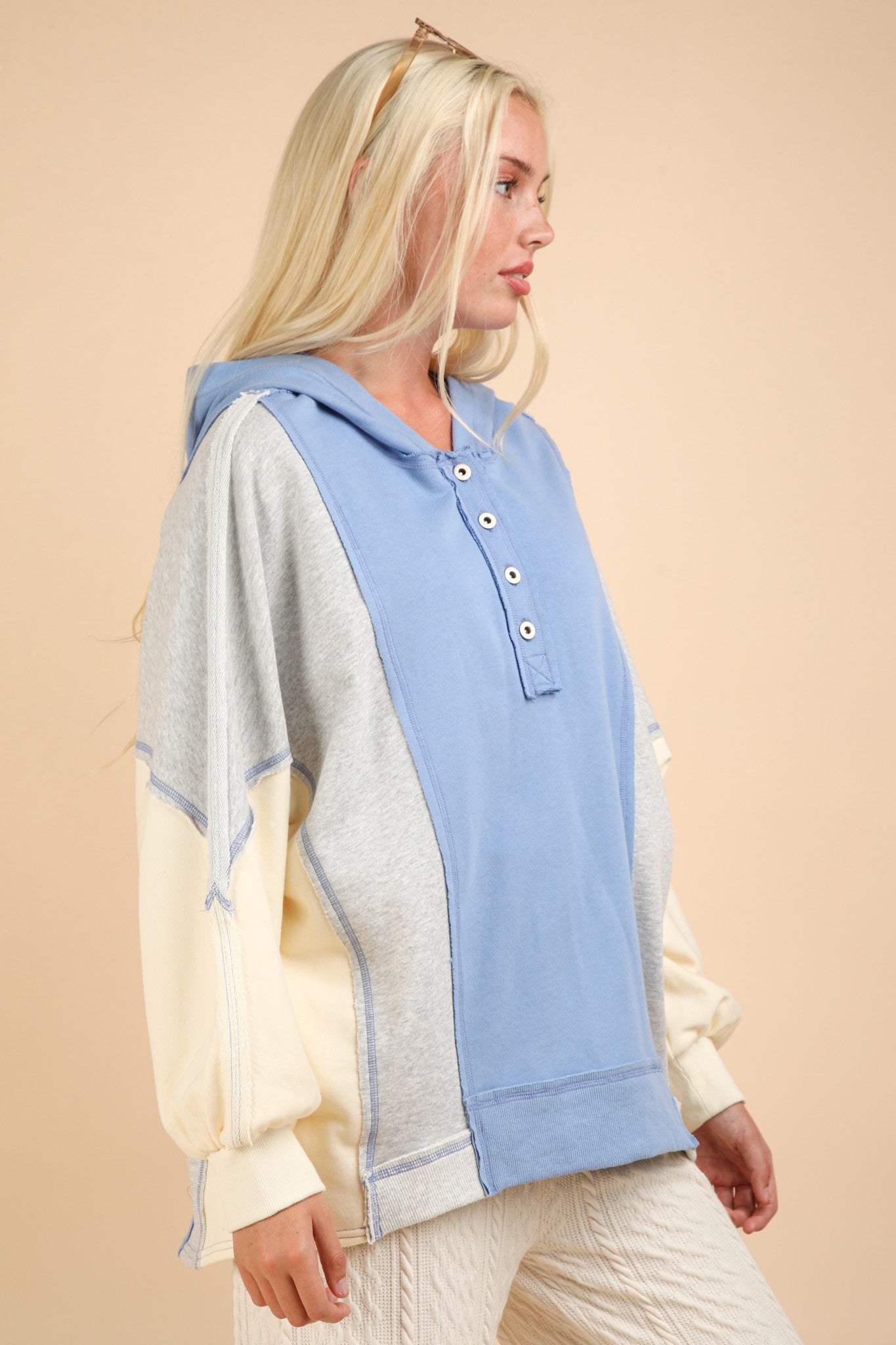 Exposed seam color block half button hoodie in shades of blue, grey, and cream with a casual design.