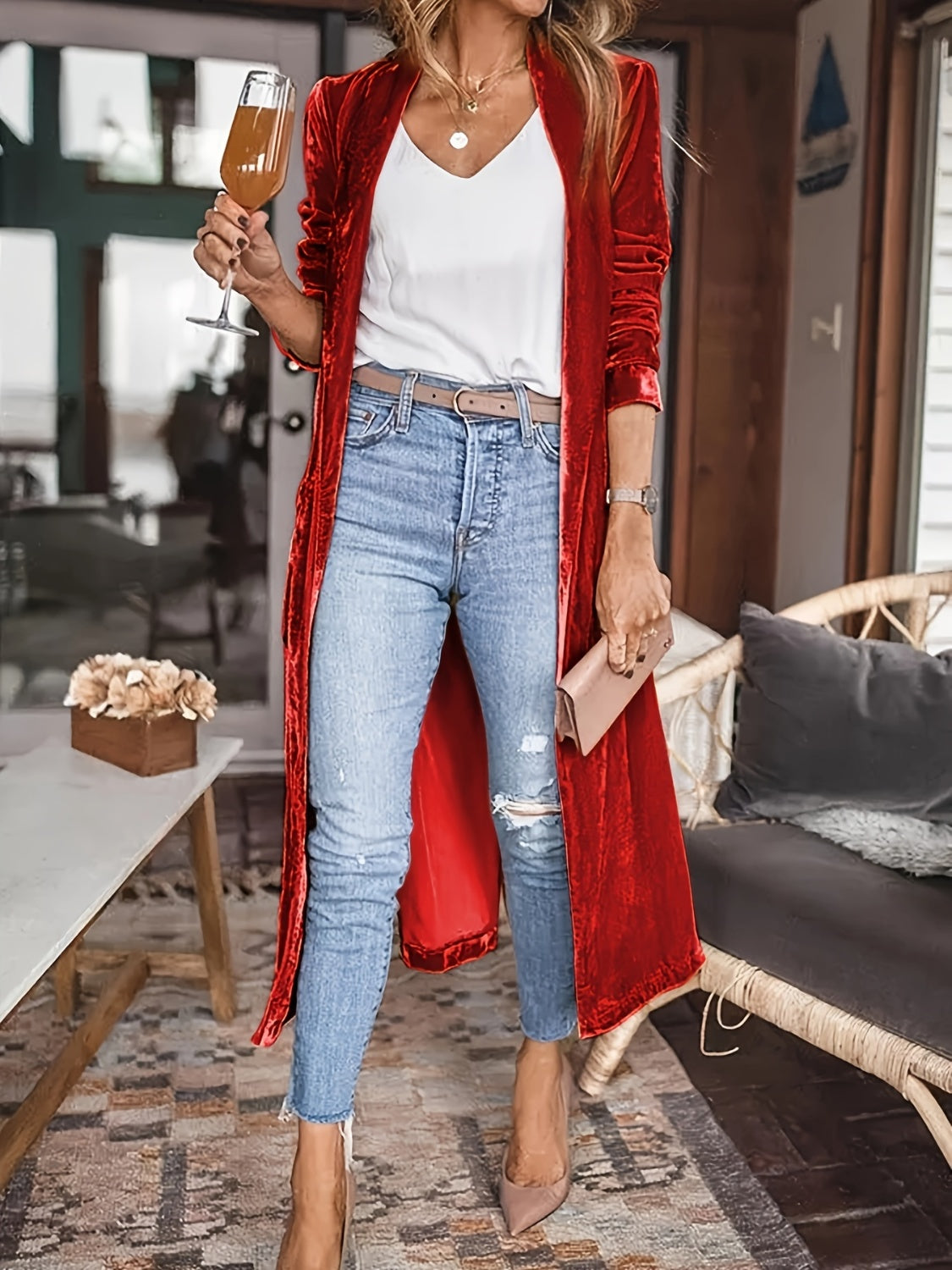 Red open front long sleeve coat paired with jeans and heels in a living room setting.