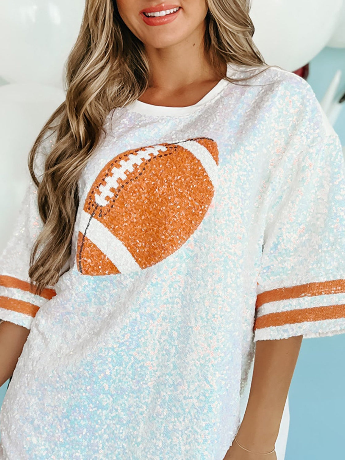 Sequin Football Oversized T-Shirt with orange football design and striped sleeves.