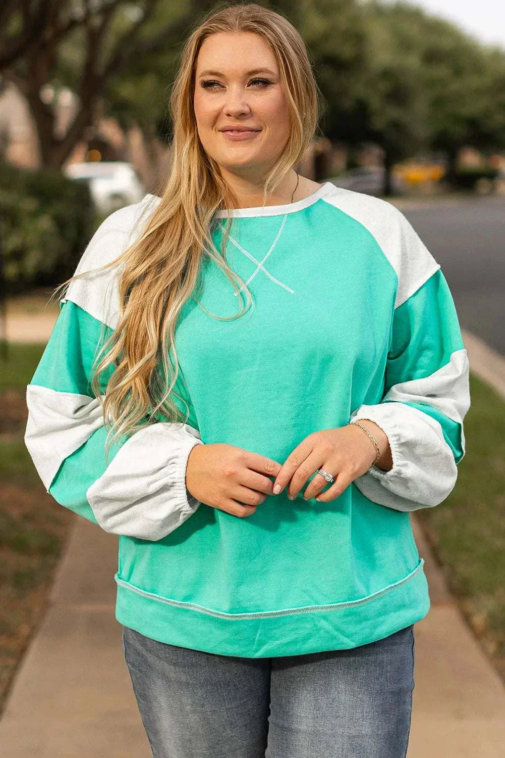 Plus size exposed seam color block long sleeve sweatshirt in green and white.