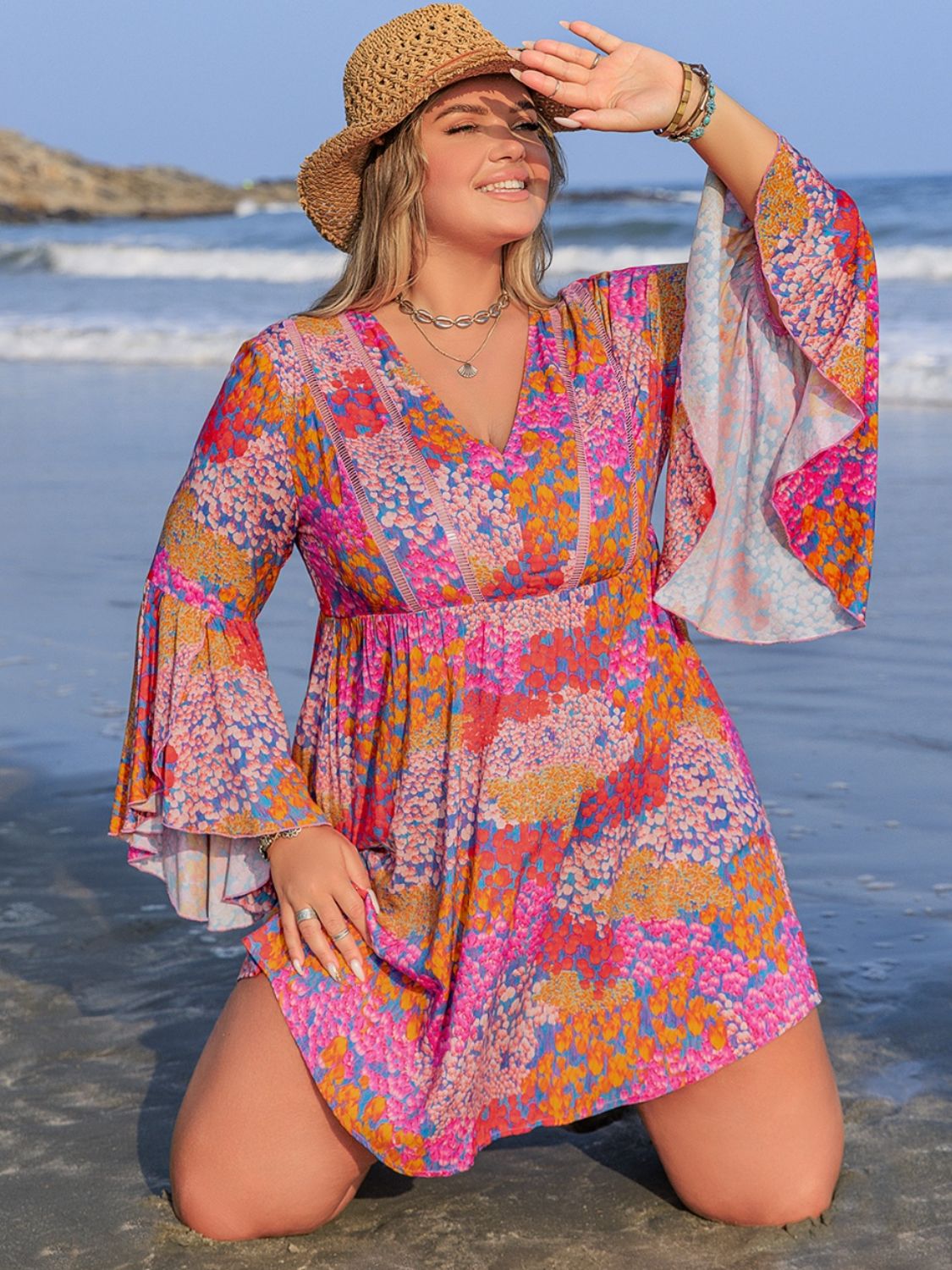 Plus Size Ruched Printed Long Sleeve Dress in vibrant colors, floral pattern, beach setting.