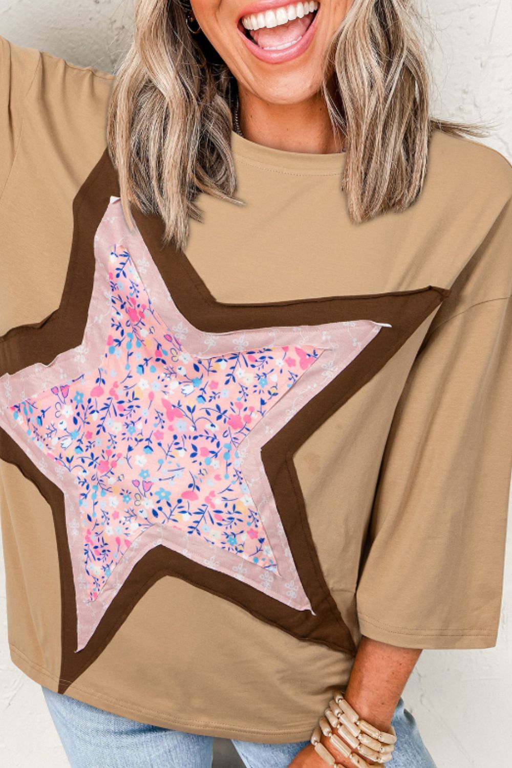 Star applique patch round neck t-shirt with floral design on beige fabric.