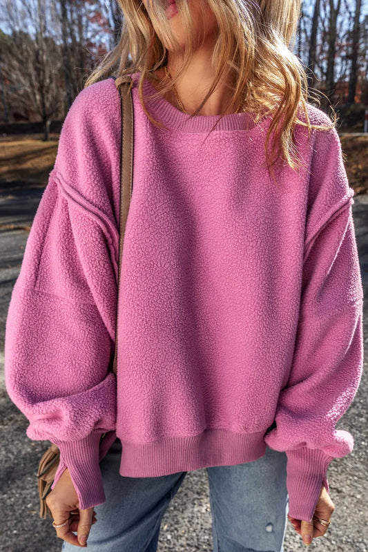 Slit round neck long sleeve sweatshirt with exposed seam design in pink.