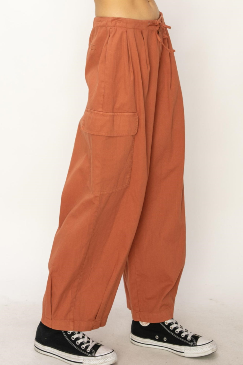 Rust-colored drawstring wide leg cargo pants with utility pockets.