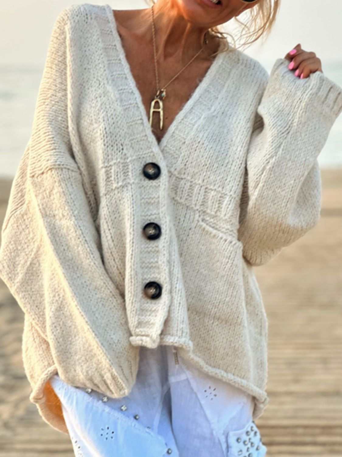 Beige V-neck buttoned cardigan with front pockets.