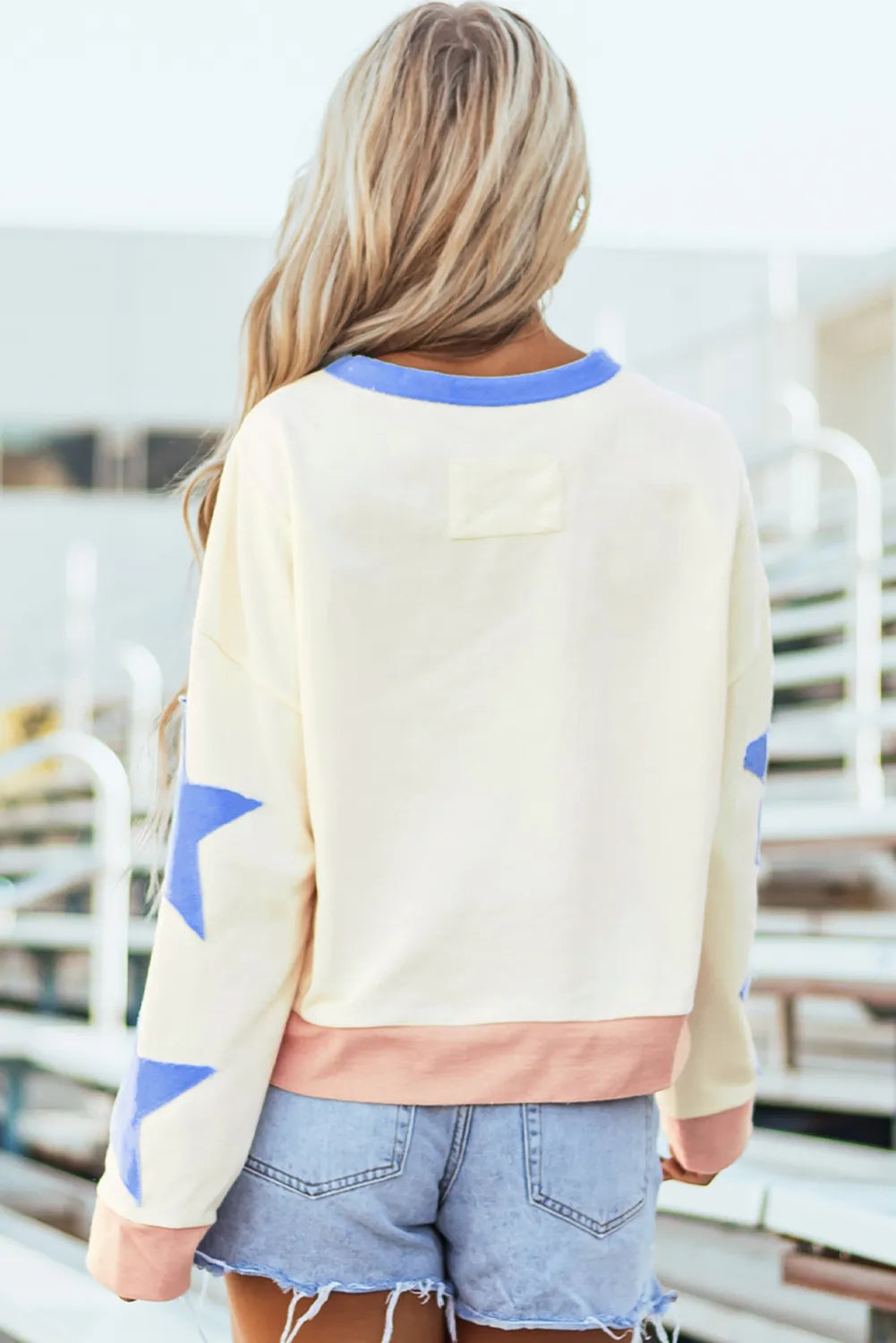 GAME DAY Star Patch Round Neck Long Sleeve Sweatshirt in light colors, worn outdoors.