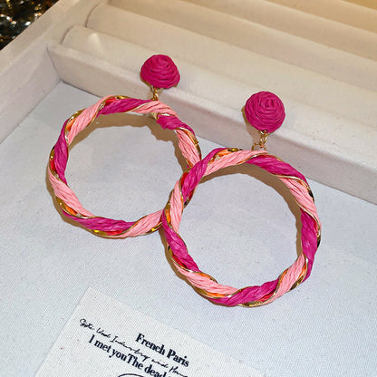 Twisted contrast grass vine earrings in pink and gold tones displayed on a jewelry box.