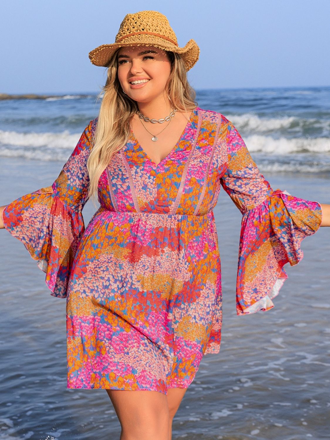 Plus size ruched printed long sleeve dress on a beach.