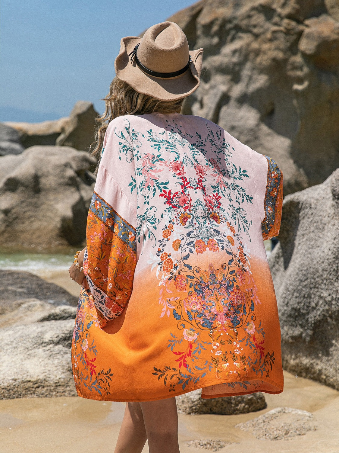 Woman wearing a printed open front long sleeve cover-up at the beach.