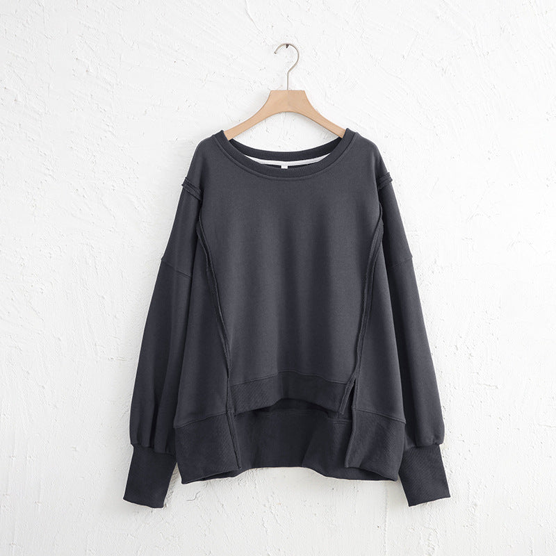 Exposed seam high-low long sleeve sweatshirt in black, featuring slit design, slightly stretchy 100% cotton material.