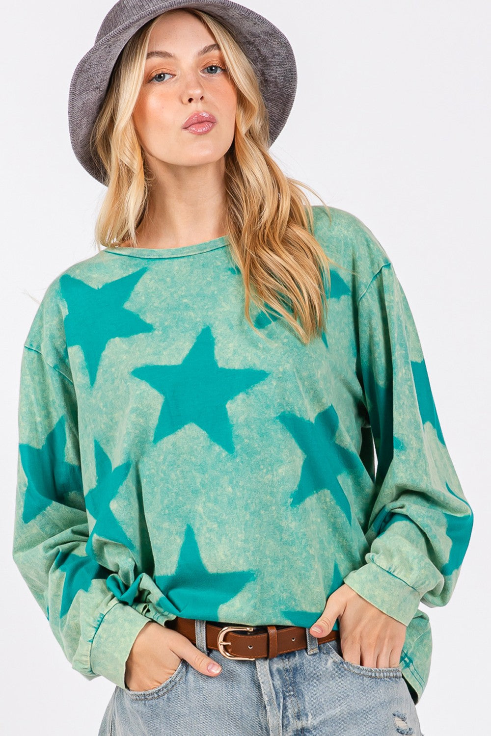 Mineral wash star pattern T-shirt with green star design on light fabric, worn by a model with jeans and hat.