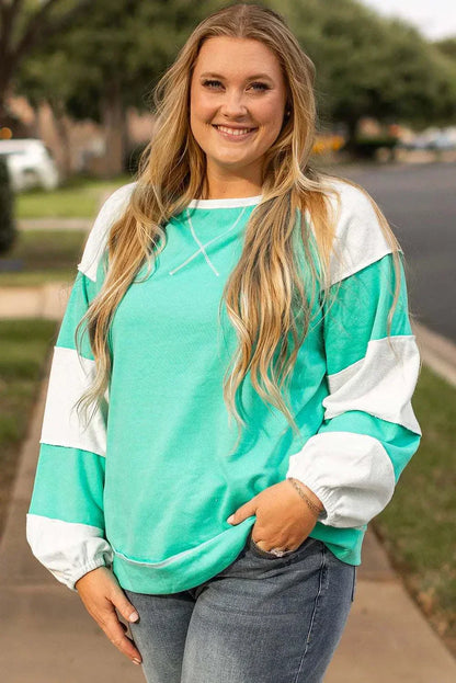 Plus size exposed seam color block long sleeve sweatshirt in teal and white.