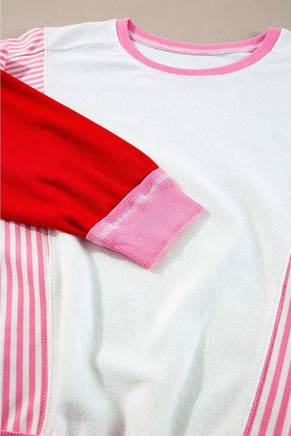 Striped color block round neck long sleeve sweatshirt with red and pink accents.