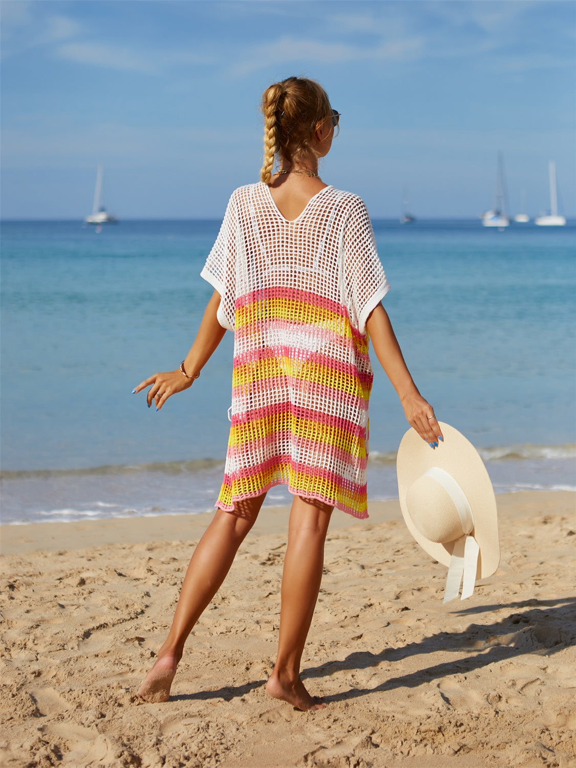 Rainbow stripe cutout swim cover up on beach with hat.