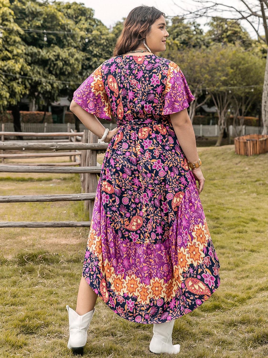 Plus Size Printed V-Neck Flutter Sleeve Midi Dress in vibrant floral pattern displayed outdoors.