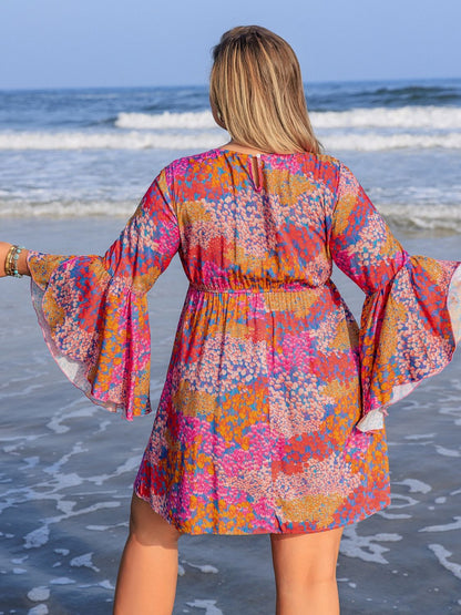 Plus size ruched printed long sleeve dress on woman at beach.