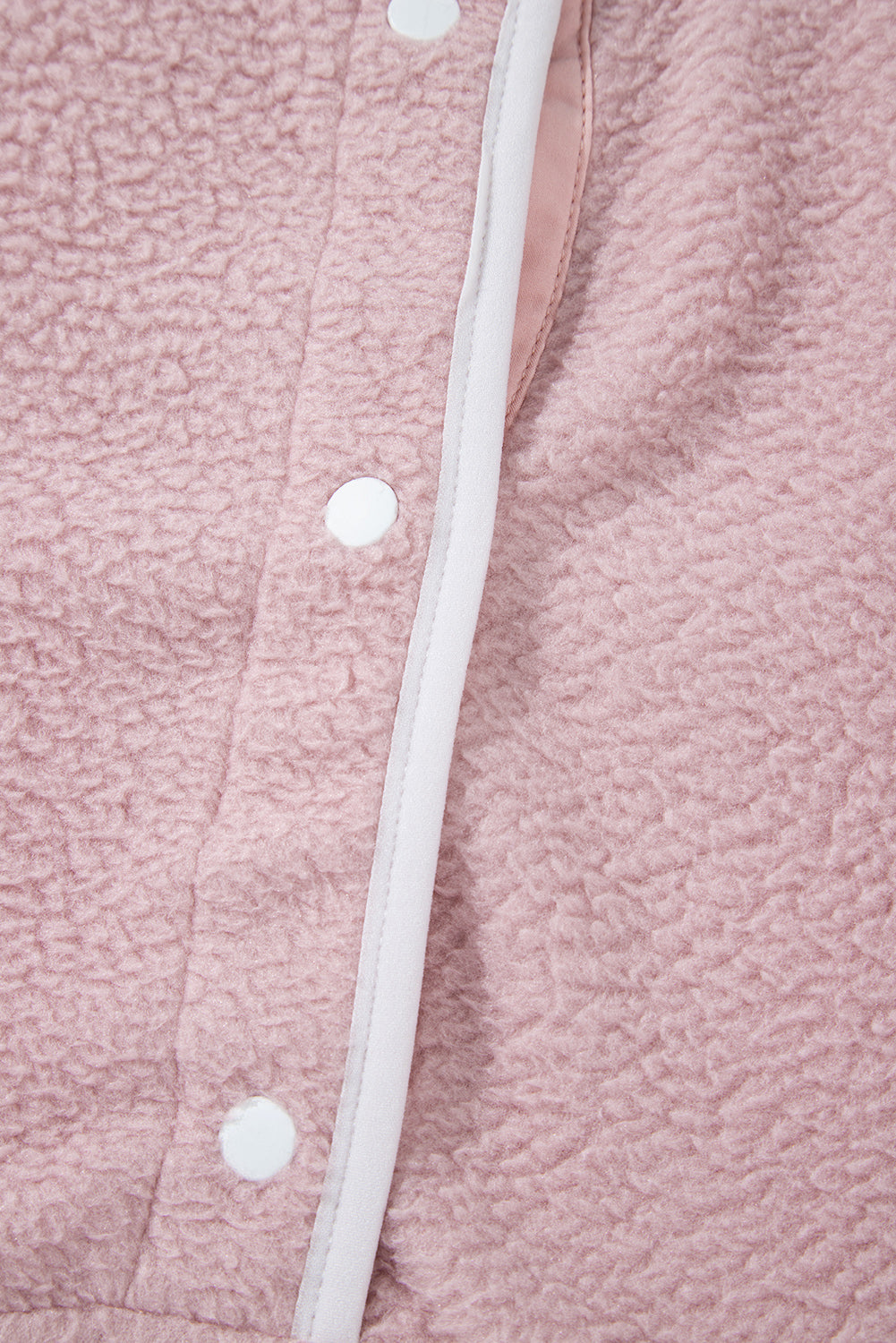 Close-up of a pink half snap long sleeve fleece jacket with white trim and snap buttons.