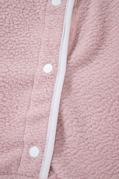 Close-up of a pink half snap long sleeve fleece jacket with white trim and snap buttons.