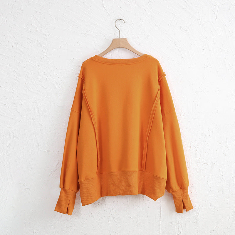 High-low long sleeve sweatshirt with exposed seams and slit, in a vibrant orange color, made from 100% cotton.