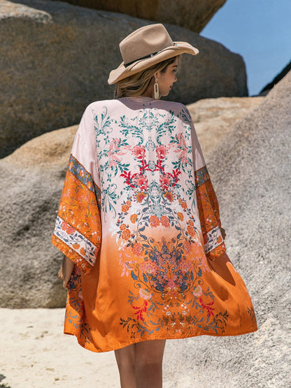 Printed open front long sleeve cover-up with floral design, worn by a woman on a beach.