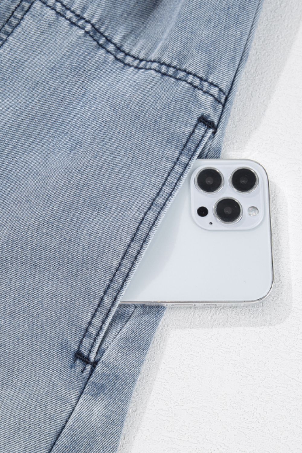 Close-up of a denim dress pocket with a smartphone, highlighting fabric detail.