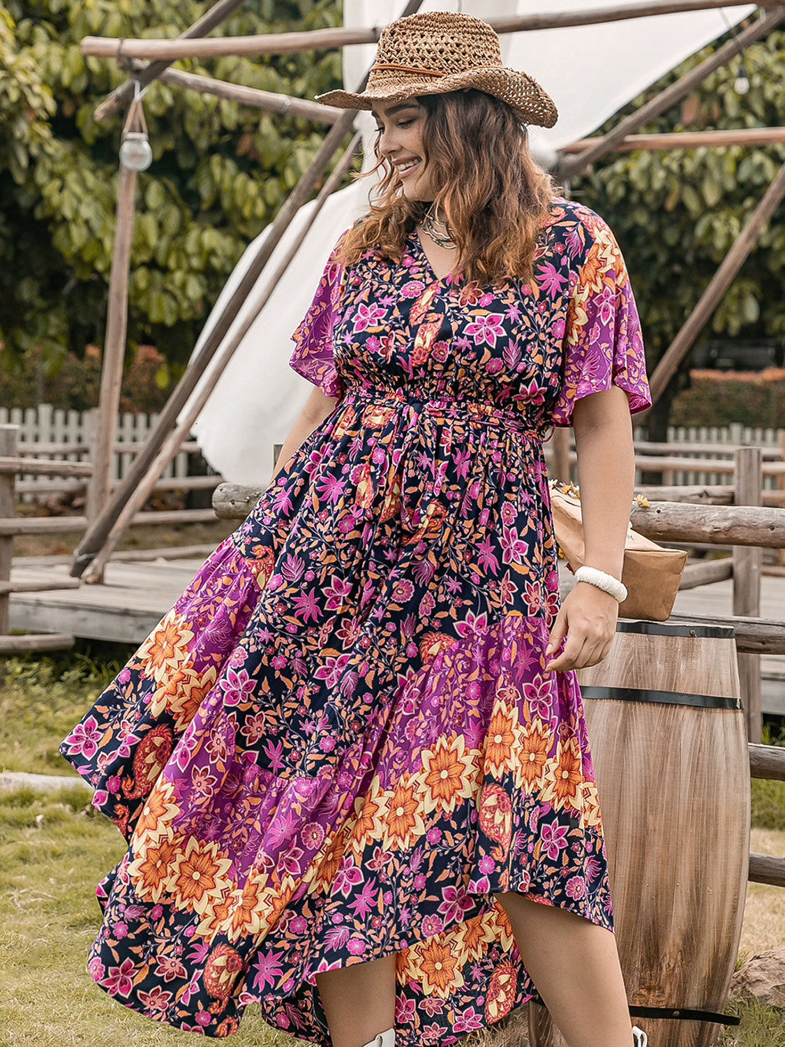 Plus size printed V-neck flutter sleeve midi dress in purple and orange floral pattern.