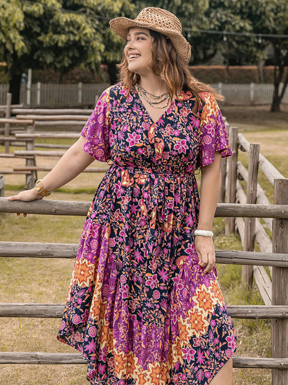 Plus size printed V-neck flutter sleeve midi dress in floral pattern.