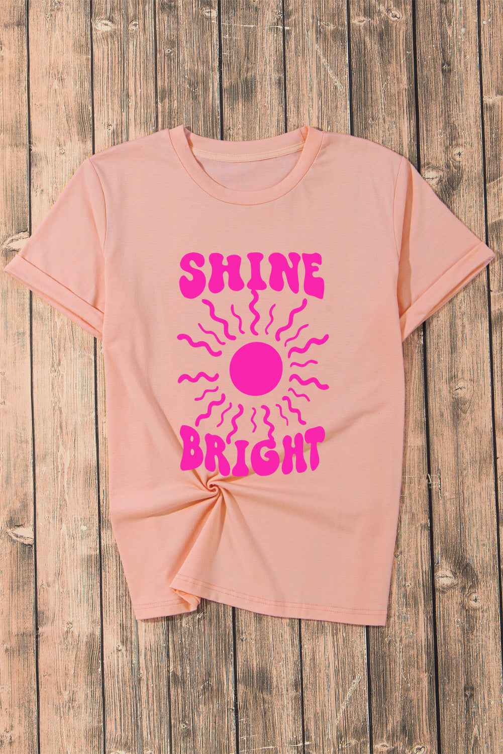 Shine Bright Graphic T-Shirt on wooden background.