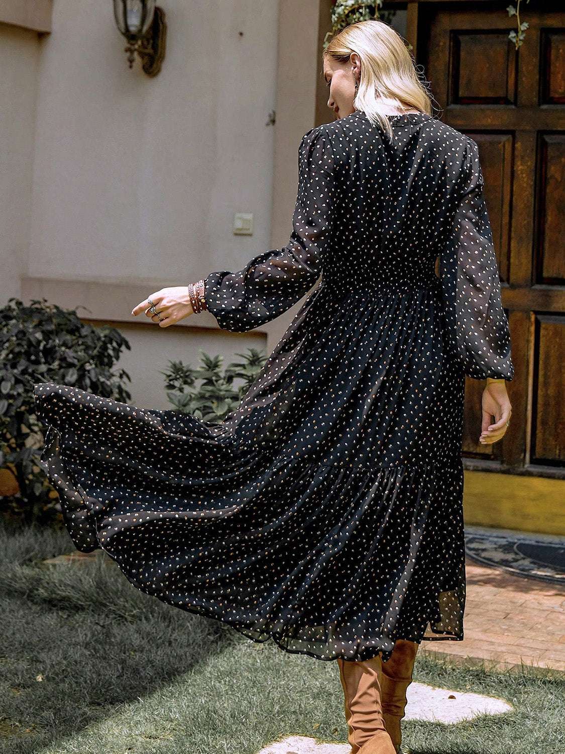 Embroidered polka dot tie neck long sleeve midi dress in black, flowing fabric, shown outdoors.