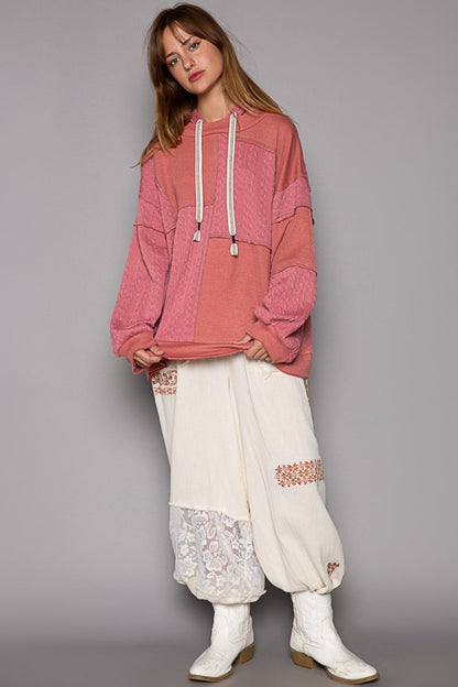 Exposed Seam Hooded Knit Top with balloon sleeves and drawstring, modeled with relaxed fit and overlock stitch details in pink.