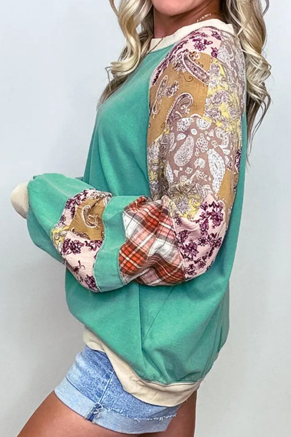 Plus size printed raglan sleeve sweatshirt in green with colorful patterned sleeves.