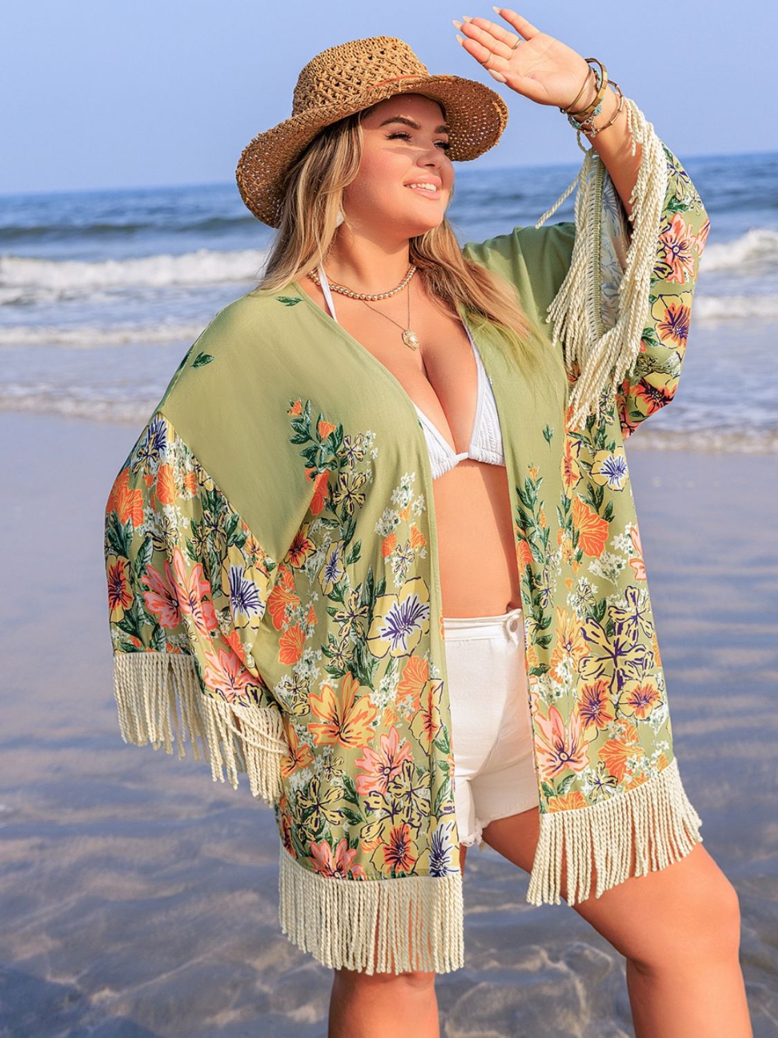 Plus size fringe open front cover-up with floral design, worn on beach.