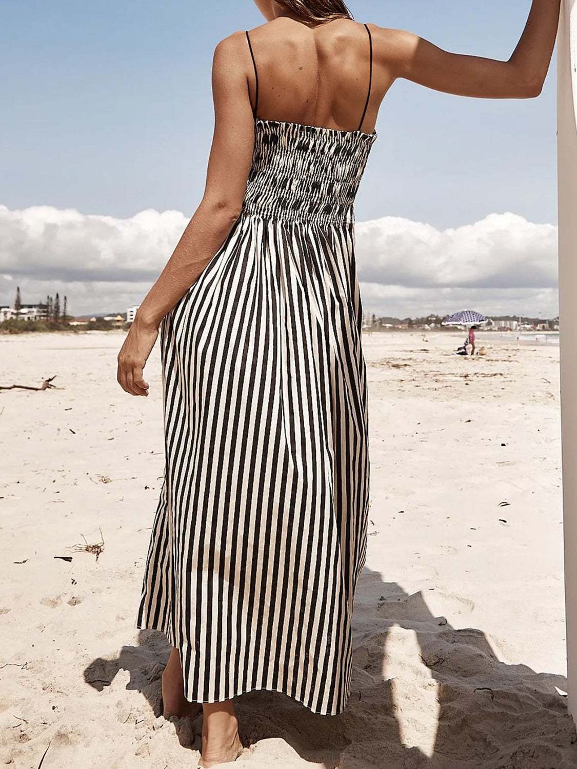 Smocked striped midi dress on beach scene.