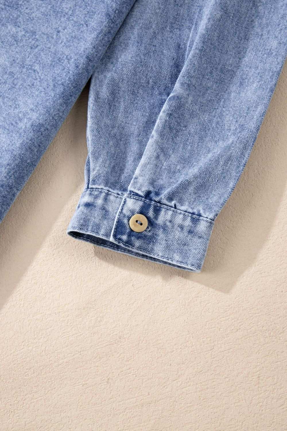 Raw hem buttoned cuff of long sleeve denim dress.