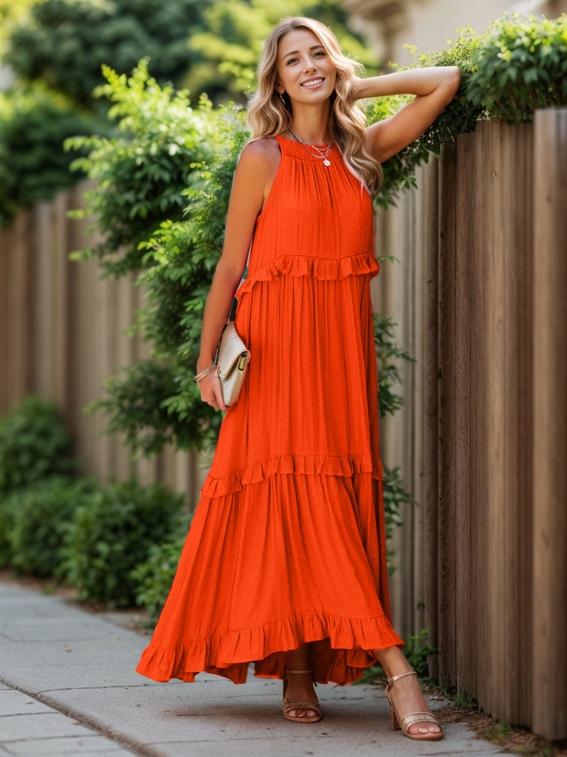 Ruffled sleeveless tiered maxi dress with pockets, bright orange color, worn by a woman outdoors.