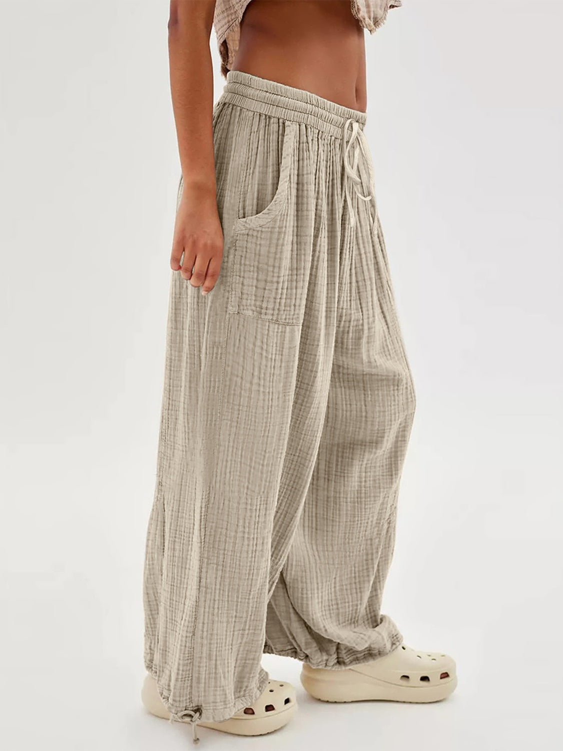 Textured tied pants with pockets in light grey, featuring a relaxed fit and drawstring waist.