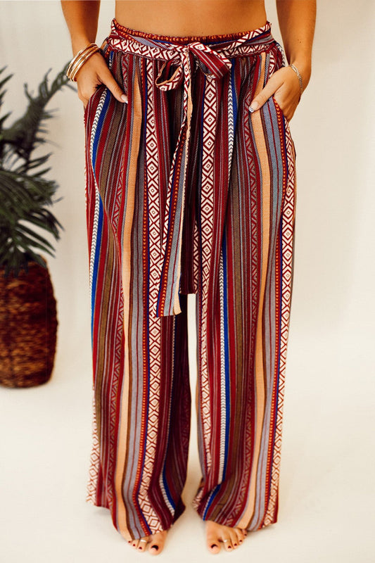 Bohemian striped wide leg pants with high waist and tie, featuring pockets.