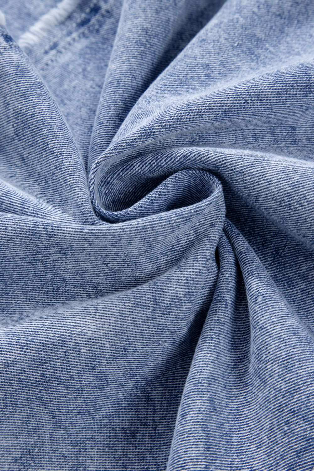 Close-up of blue denim fabric with raw hem detailing.