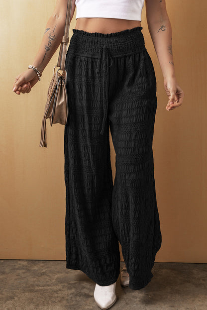 Black textured wide smocked waist loose fit pants with a relaxed silhouette.